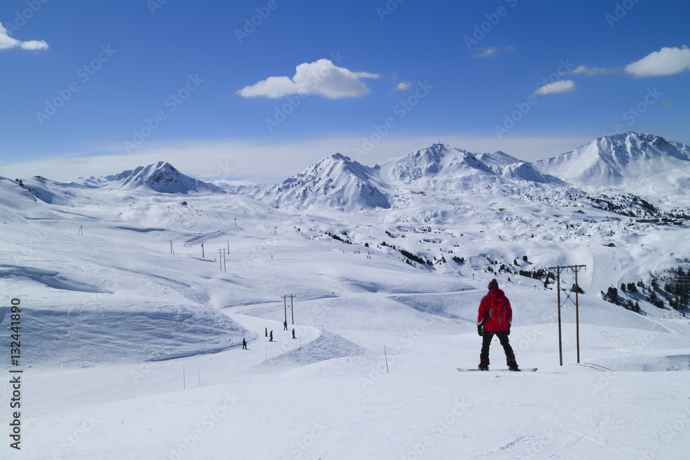 Snowboarding and skiing on fresh snow slopes in an alpine valley, Paradiski, Plagne, Alps, France