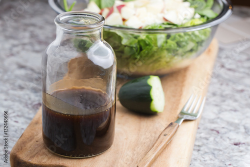 a glass bottle with salad dressing consisting of balsamic vinegar, honey and olive oil