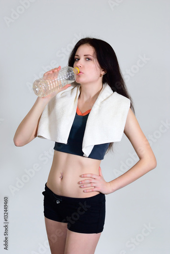 The girl drinks water with a towel on a white background