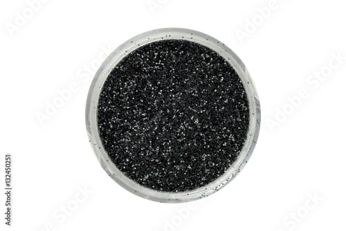 Black glitter particles in open container, view from above