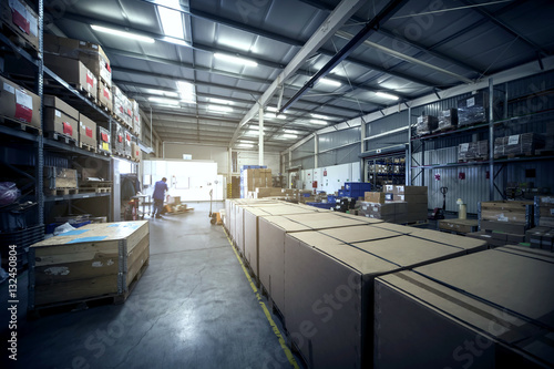 warehouse interior with paper boxes and worker with forklift in blue vintage color tone photo