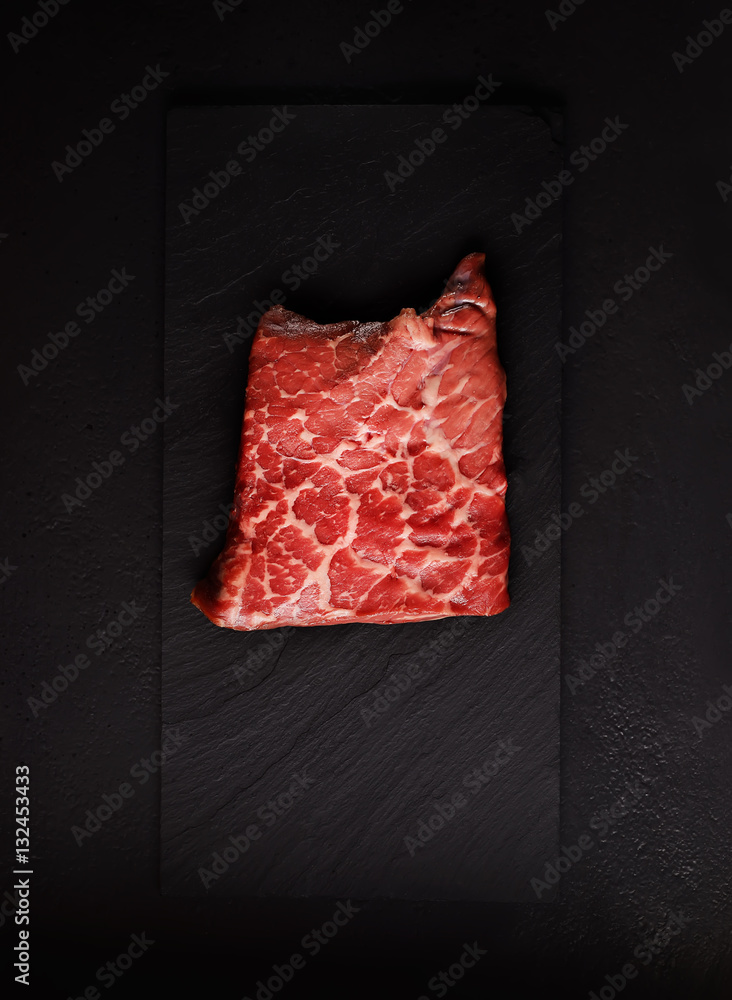 raw chunks of marble beef on a black  background
