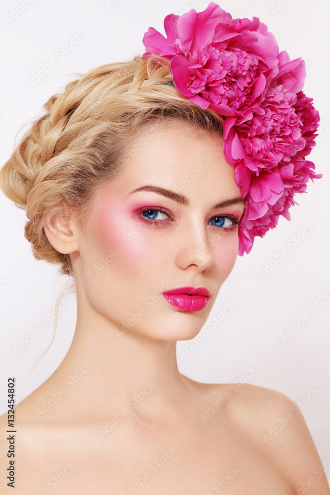 Portrait of young beautiful healthy blonde woman with clean make-up and pink peony flowers in her hair