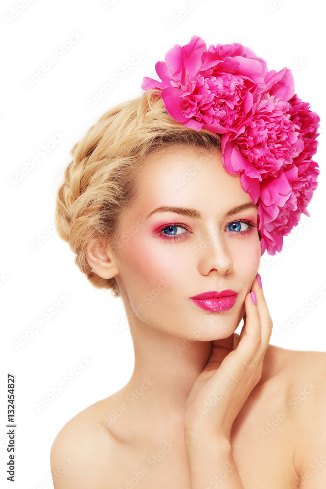 Portrait of young beautiful healthy blonde woman with clean make-up and pink peony flowers in her hair touching her face