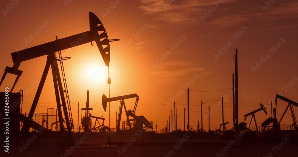 The sun rises behind a large oil field The sun rises behind a large oil field