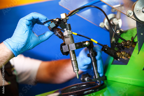 Professional mechanic testing diesel injector in his workshop.