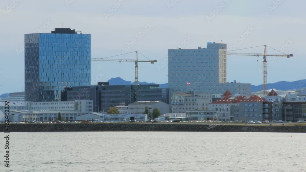 panorama of quay of Reykjavik with modern buildings, moving cars, mountains and oceanic water panorama of quay of Reykjavik with modern buildings, moving cars, mountains and oceanic water