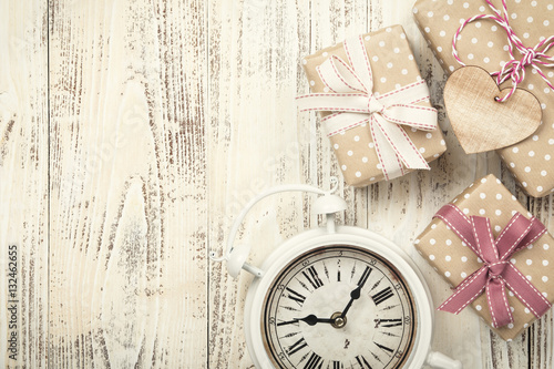 Gift boxes and alarm clock on wood