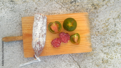 Salami und  grüne Tomaten auf Holzbrett Vogelperspektive photo