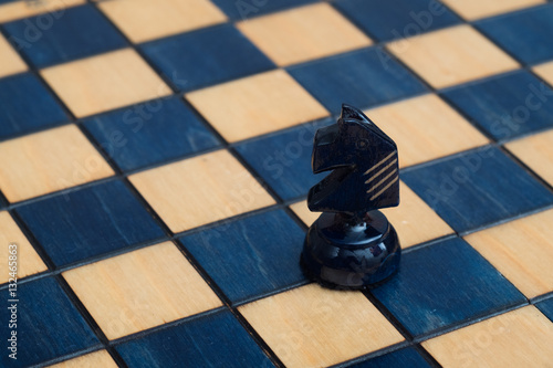 Dark blue knight on wooden chessboard