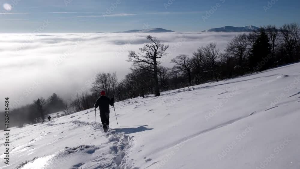 Travellers With Backpacks Make a Winter Hike Above the Clouds With a View of the Distant Peaks by a Coast of the Cloud Sea Travellers With Backpacks Make a Winter Hike Above the Clouds With a View of the Distant Peaks by a Coast of the Cloud Sea