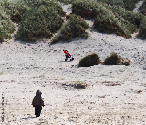 Child with stroller on beach in Denmark