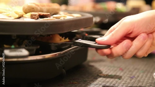 Mann nimmt Pfännchen aus dem Raclette-Ofen an Silvester