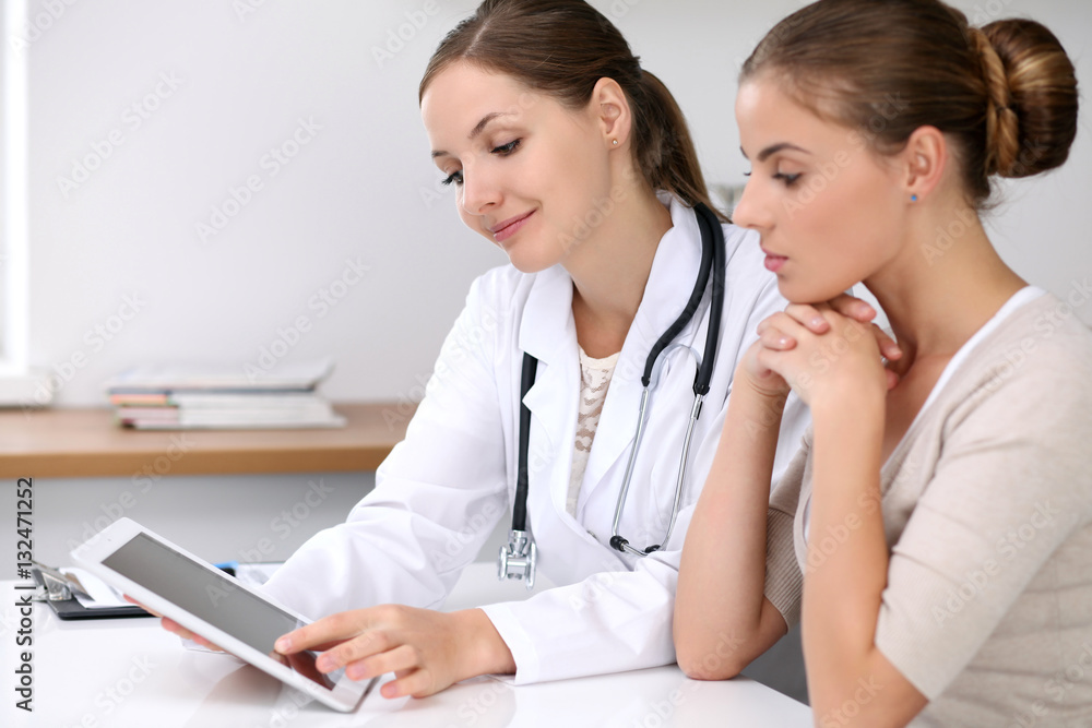 Doctor and patient sitting at the desk. Physician pointing into laptop computer. Medicine and health care concept Doctor and patient sitting at the desk. Physician pointing into laptop computer. Medicine and health care concept