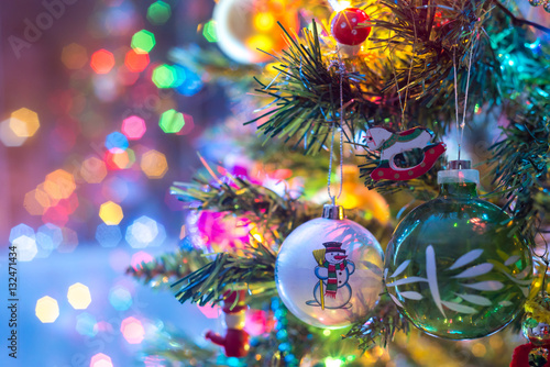 Part of Christmas tree, with colorful glass balls, small decorations and colorful light reflections