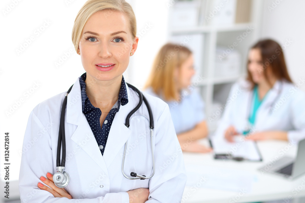 Female doctor smiling on the background with patient and his physician in hospital Female doctor smiling on the background with patient and his physician in hospital