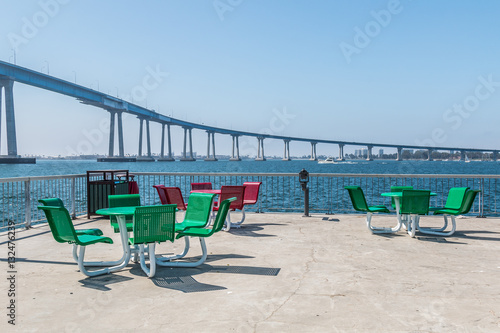 Dining area on the viewing pier at Cesar Chavez Park in San Diego, California, with Coronado bridge in the background. photo