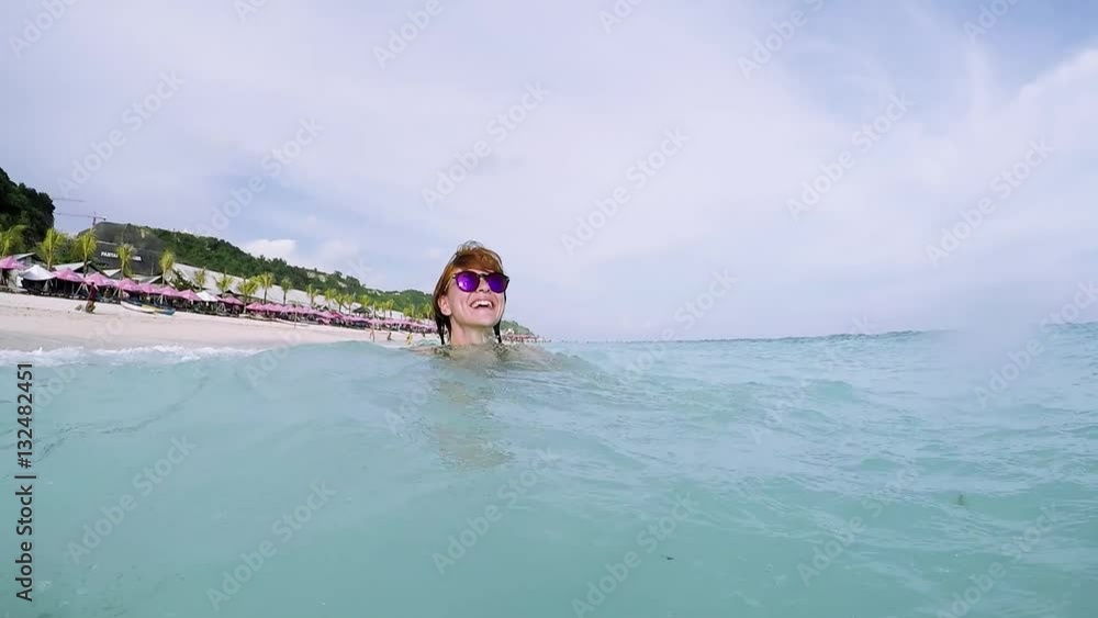Slow motion of cute woman smiling while she is in the ocean on the beach of tropical Bali island, Indonesia. Pandawa beach. Pantai Pandawa, Asia. Sunny day. Slow motion of cute woman smiling while she is in the ocean on the beach of tropical Bali island, Indonesia. Pandawa beach. Pantai Pandawa, Asia. Sunny day.