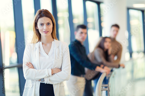 Businesswoman posing while others business people talking in background photo