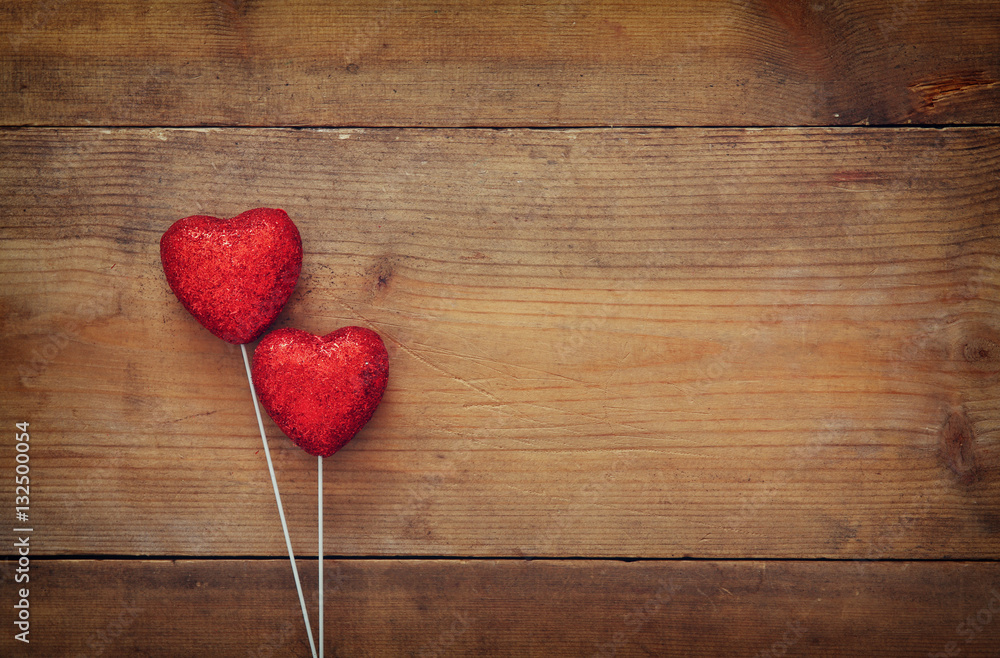 Couple of red glitter hearts on wooden background Couple of red glitter hearts on wooden background