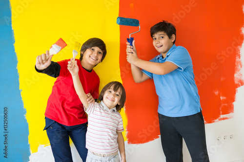Adorable boy in bright paint with mess of paint child on wall