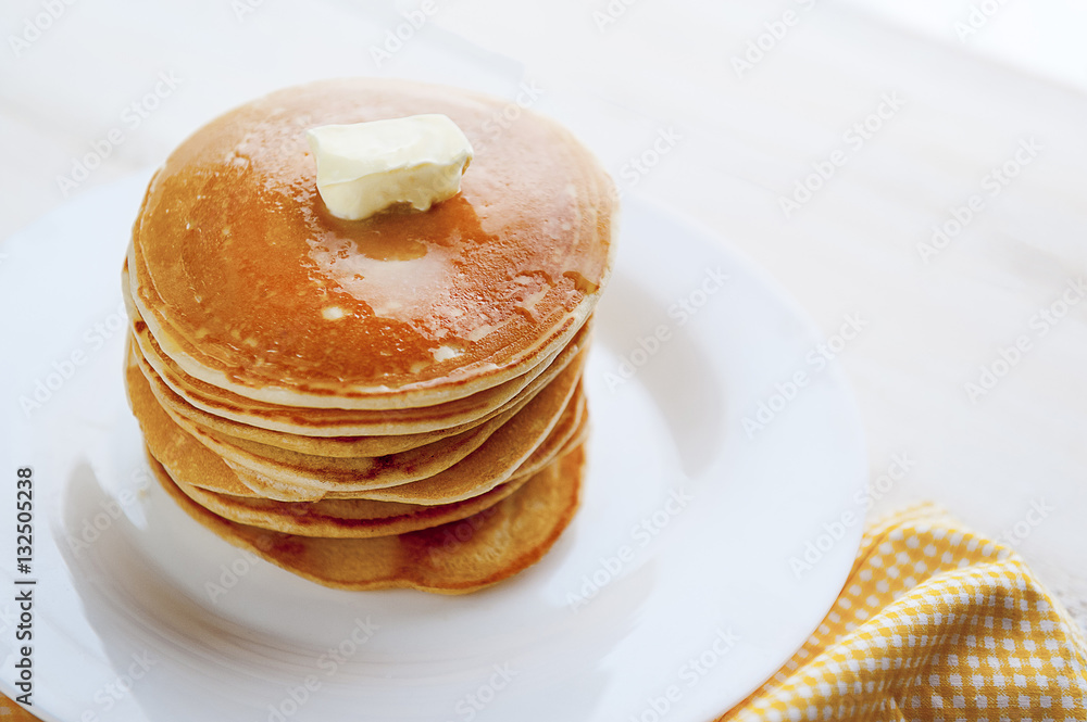 Pancake on a white plate with a piece of butter on a wooden background Pancake on a white plate with a piece of butter on a wooden background
