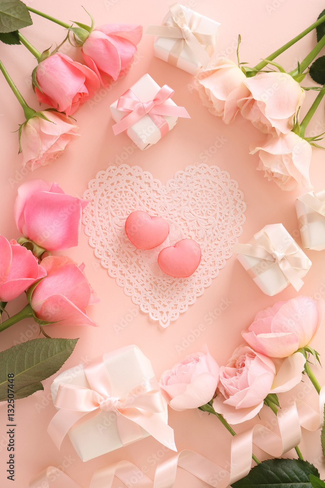Pink macaroons with beautiful pink tone roses and gift boxes on pastel pink background,top view