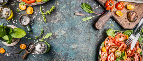 Healthy vegetarian salad making preparation with tomatoes on rustic background, top view, banner, copy space