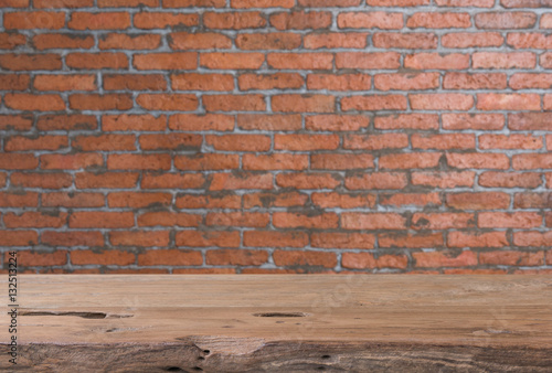 Teak wood table top with grunge brick wall blurred background