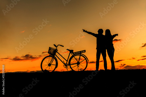 Silhouette of sweet couple in love happy time and bicycle in bea