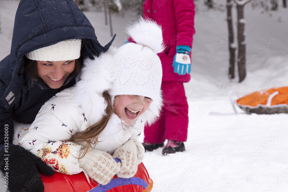 Happy mother and daughter laughing and rolling with snow hill. Happy mother and daughter laughing and rolling with snow hill.