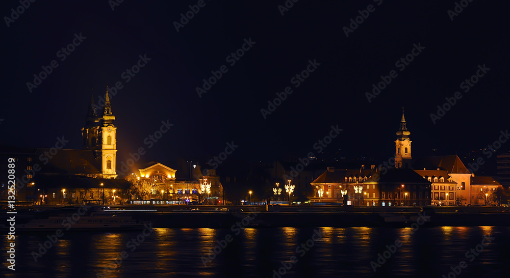 View on the illuminated St. Anne's Church and nearby houses near the river on a winter night. Budapest.