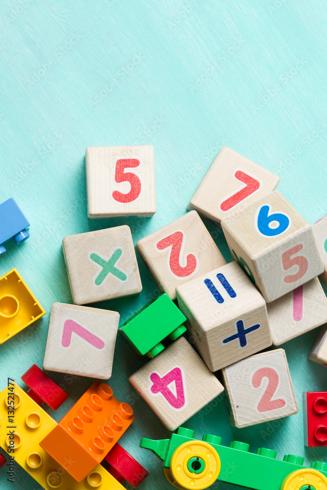 Wooden cubes with numbers and colorful toy bricks on a turquoise wooden background. Wooden cubes with numbers and colorful toy bricks on a turquoise wooden background.