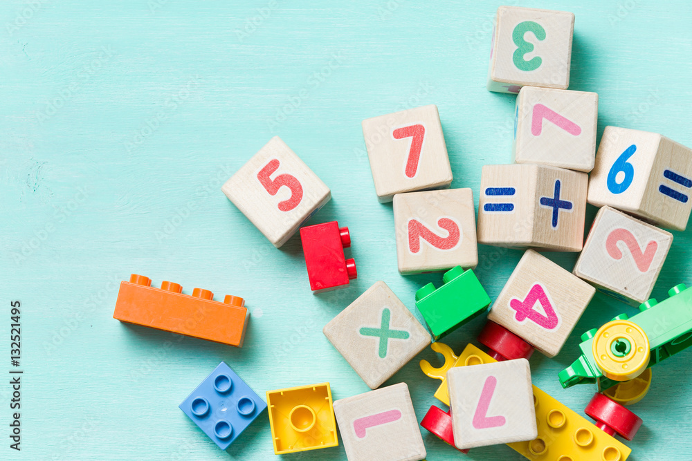 Wooden cubes with numbers and colorful toy bricks on a turquoise wooden background. Wooden cubes with numbers and colorful toy bricks on a turquoise wooden background.