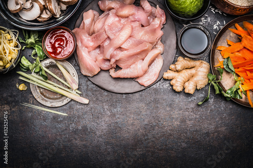 Asian cooking preparation with  ingredients : chicken Strips, Shoots, vegetables and spices on dark rustic background, top view, border