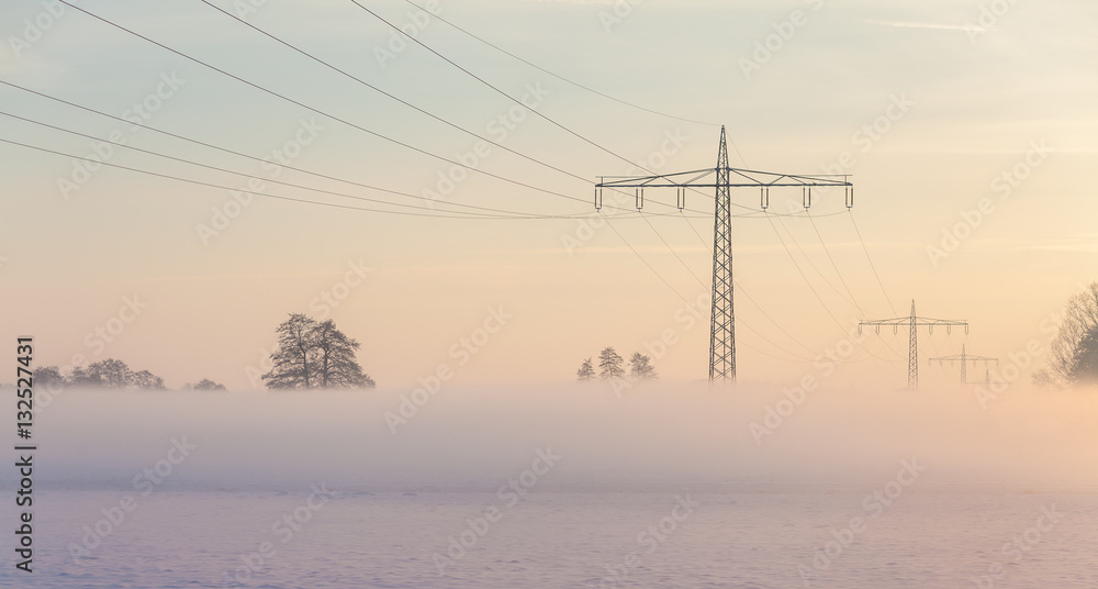 Fog and power supply lines during sunrise in the winter