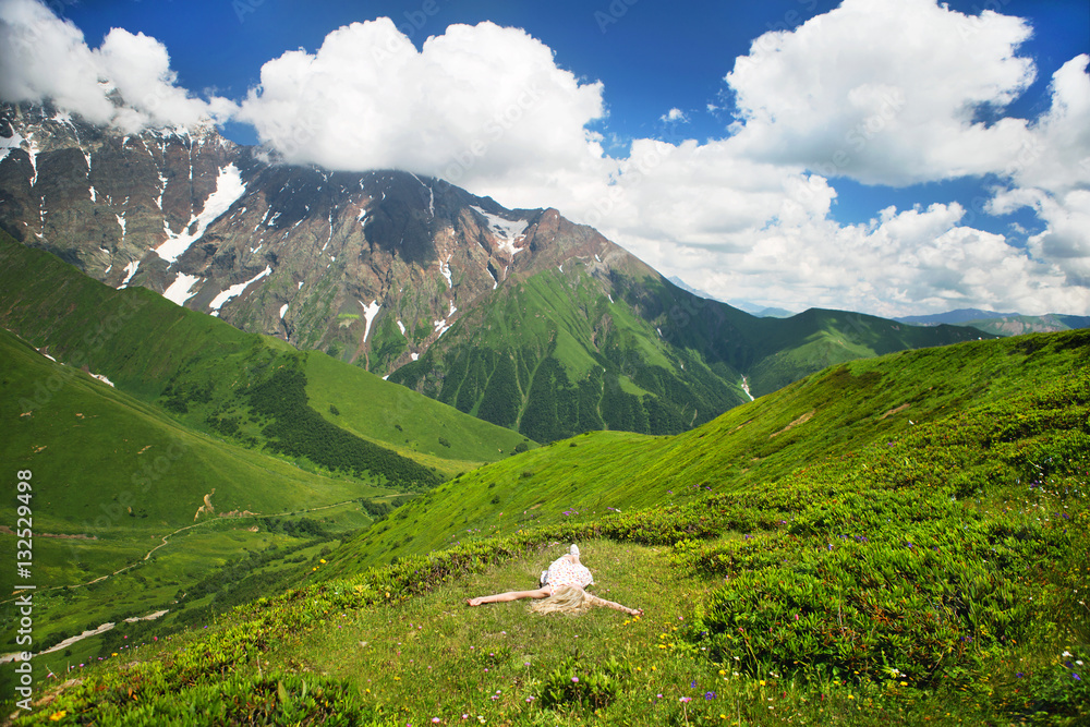 Woman lies on a grass among Caucasian mountains