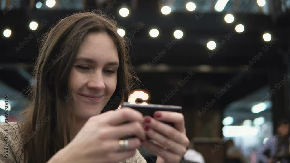 Closeup portrait. Woman using her smartphon touchscreen device in modern cafe lights in the background 4k Closeup portrait. Woman using her smartphon touchscreen device in modern cafe lights in the background 4k