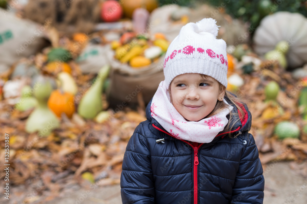 Beautiful little girl against a pile of pumpkins Beautiful little girl against a pile of pumpkins