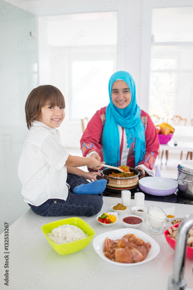 Muslim traditional woman with little son in modern white kitchen Muslim traditional woman with little son in modern white kitchen