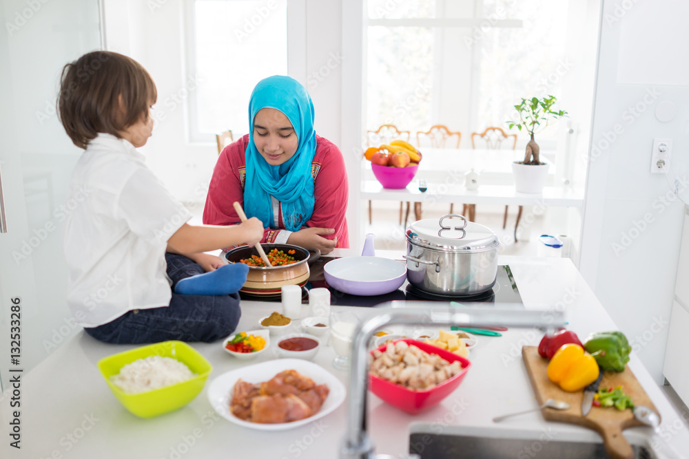 Muslim traditional woman with little son in modern white kitchen Muslim traditional woman with little son in modern white kitchen