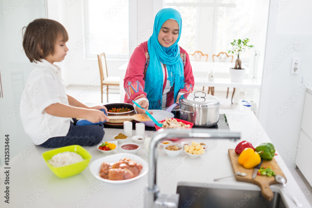Muslim traditional woman with little son in modern white kitchen Muslim traditional woman with little son in modern white kitchen