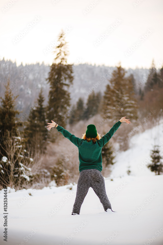 Happy girl jumping in the winter snowy mountains.
