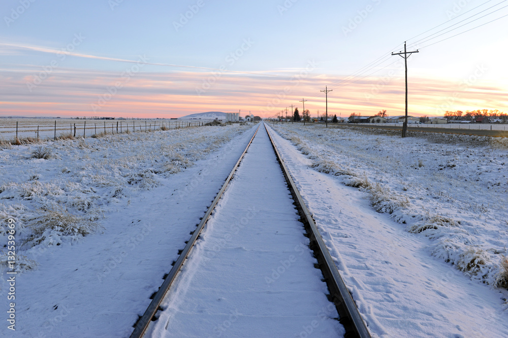 Snow covered Train tracks into the horizon at sunset