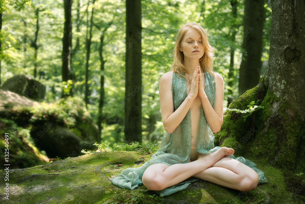 Freckles, red-haired woman meditating and doing yoga  in fairy forest 