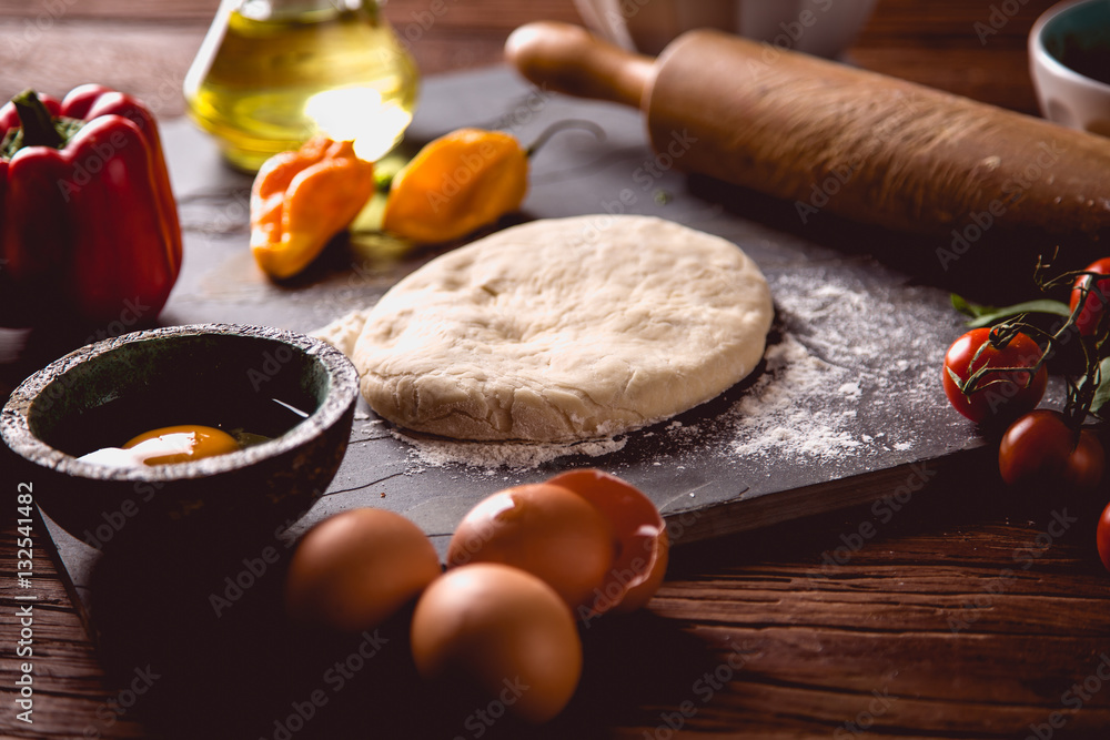 Fototapeta premium Preparing home pizza on wooden table with ingredients