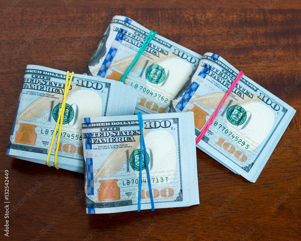 Obraz premium Stashes of hundred dollar bills on wooden table