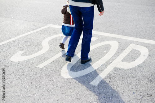 Back view of parent with child walking on sunny road outdoors background. Childcare, love and safety lifestyle