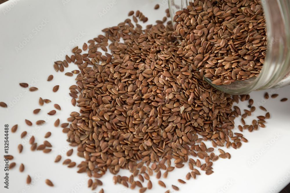 Flax seeds spilling out of container, close up Flax seeds spilling out of container, close up