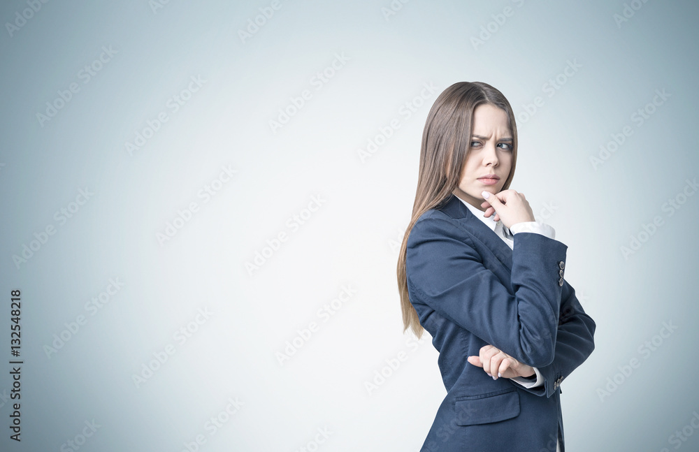 Frowning businesswoman near a gray wall